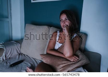 Woman sitting on sofa watching tv in dark room