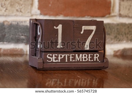 Brown Wooden Calendar Showing the Date of September 17th with Brick Background