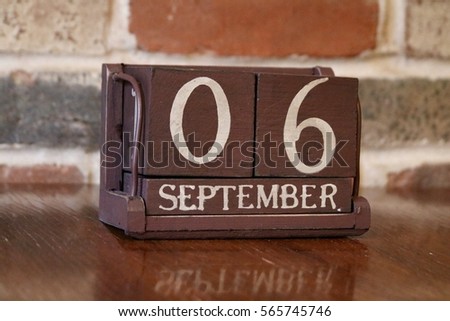 Brown Wooden Calendar Showing the Date of September 6th with Brick Background