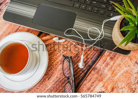 Wooden table with a smartphone, computer and a Cup of tea. The view from the top,image with selective focus. 