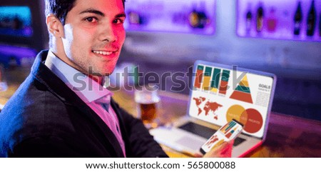 Computer graphic image of business presentation with charts and map against portarit of businessman holding mobile phone