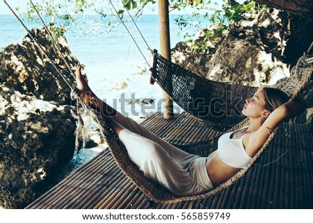 Woman relaxing in the hammock on tropical beach, hot sunny day Royalty-Free Stock Photo #565859749
