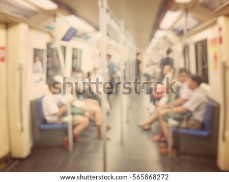 Blurred image of city people lifestyle background, inside the train standing walking and sitting using internet with smartphone or mobile phone on the way go to work in the morning. vintage tone.