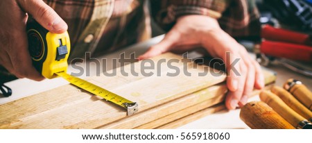 Joinery tools. Carpenter holding a measure tape on the work bench Royalty-Free Stock Photo #565918060