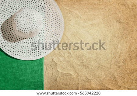 Top view of sandy beach with towel frame and summer accessories. Background with copy space and visible sand texture. Left border made of towel