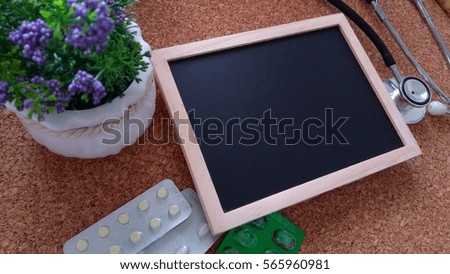 Stethoscope, flower,  Chalk board and  Medicine  on a wooden table. Medical and health care concept.