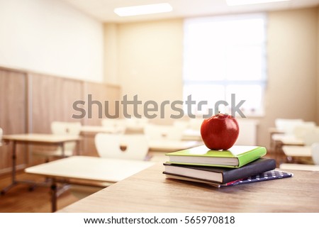 School teacher's desk with stack of books and apple Royalty-Free Stock Photo #565970818