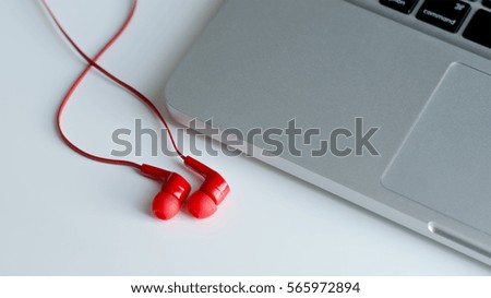 Red earphone with notebook on the white table.