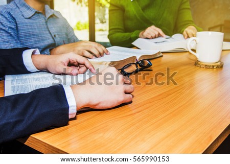 Christian business man and women reading bible in the office,  hand on burred open bible on wooden table, Christian concept or background