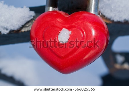 A closed lock in the shape of a red heart on a background of rusty metal