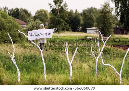 Scarecrow with a poster "The bar is open" in the neck. Wedding concept.