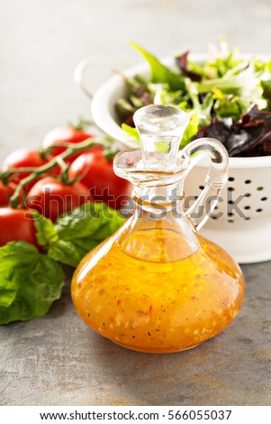 Italian vinaigrette dressing in a vintage bottle with fresh vegetables on the table. Royalty-Free Stock Photo #566055037