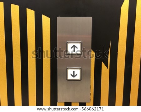 Keypad elevator Up or Down Choices with a yellow and black wall 