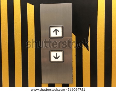 Keypad elevator Up or Down Choices with a yellow and black wall 