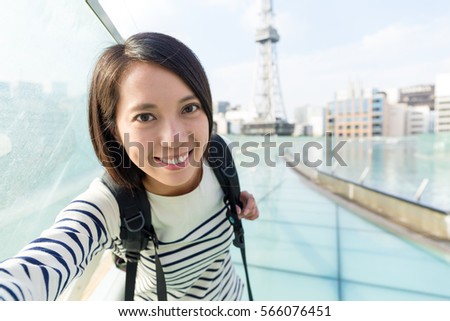 Young woman holding digital camera to take selfie