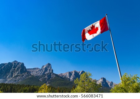 Canada's National Flag, and the Rocky Mountains. Maple Leaf represents the nations symbol the brilliant red and white are the official colors of Canada Celebrating of 150 years of confederation Royalty-Free Stock Photo #566083471