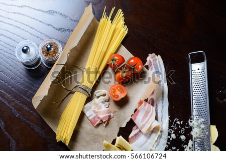 Food ingredients for Italian spaghetti, tomatoes and bacon on black background