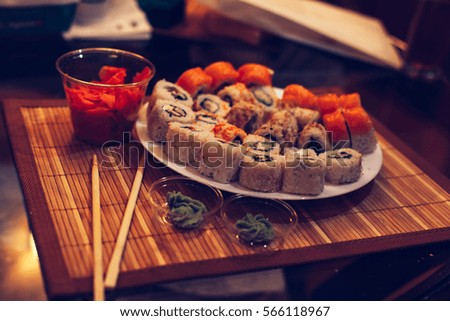 Various kinds of Classic Japanese sushi Set rolls with ginger and avocado on a plate served on glass rattan table on a bamboo tray close up. prepared from raw fish and a rice. vintage toned pic