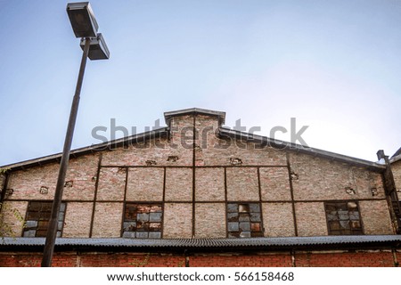 Street light post in front of old industrial brick building with small dirty and broken windows against the clear blue sky