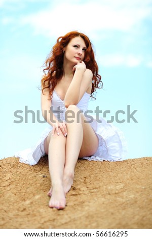 Cute young smiling female with red hairs sitting on ground