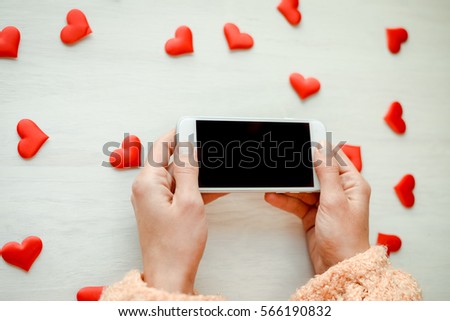 Woman holding smartphone over love heart background