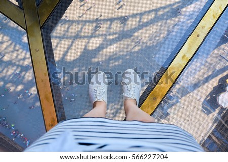selfie legs in white sneakers (shoes) and a white skirt on a glass floor Eiffel Tower. View from above.