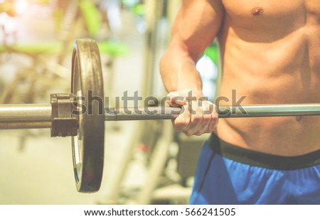 Athlete lifting weight in american gym club with personal coach - Young man doing strength workout - Fitness,concentration and bodybuilder concept - Focus on man hand - Warm cinematic filter