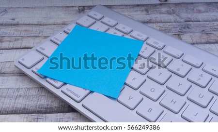 Closeup of colorful sticky post note on a office computer keyboard with copy space on wooden background. Selective focus.