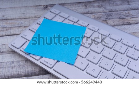 Closeup of colorful sticky post note on a office computer keyboard with copy space on wooden background. Selective focus.