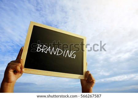 Man holding chalkboard written with BRANDING on blue clouds sky background.