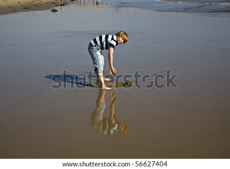 boy at the beach in Venice with reflecting picture in wet sand