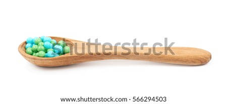Spoon full of green and blue sugar candy sprinkle balls isolated over the white background