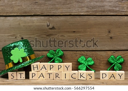 Happy St Patricks Day wooden blocks with shiny shamrocks and leprechaun hat on a wooden background