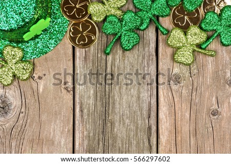 St Patricks Day top border of shamrocks, gold coins and leprechaun hat over rustic wood