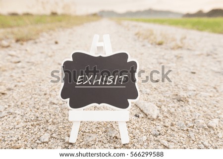 Exhibit  signboard over rocky road with paddy field  background