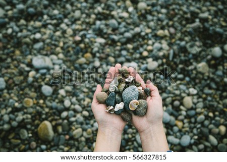 Girl holding in hands small sea stones, gravel	