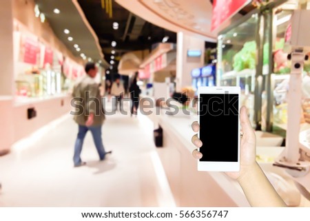 Man use mobile phone, blur image of restaurant in the mall as background.