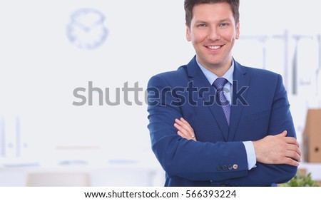 Business man or manager standing against his desk at office with  arms folded  
