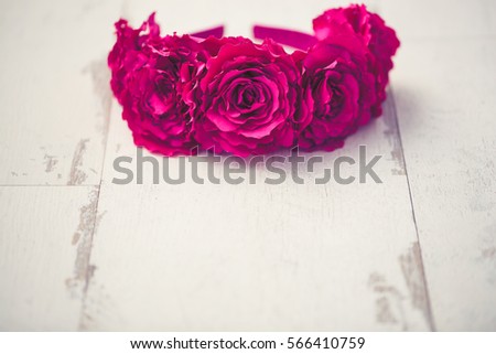 Handmade wreath made of artificial pink rose flowers on a wooden background.Shallow depth of field,macro closeup with copy space on bottom.Artificial flower on handcrafted diadem head wear for women