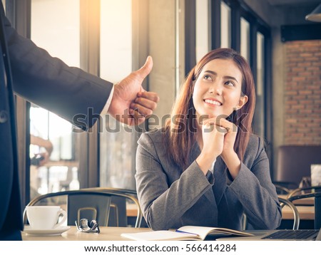 Boss/employer admires to young Asian businesswoman/staff/employee with smiling face for her success and good/best in work.  Royalty-Free Stock Photo #566414284
