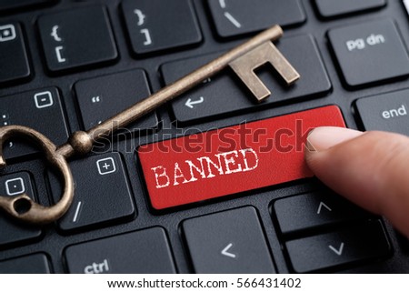 Closed up finger on keyboard with word BANNED Royalty-Free Stock Photo #566431402