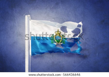 Torn flag of San Marino flying against grunge background.