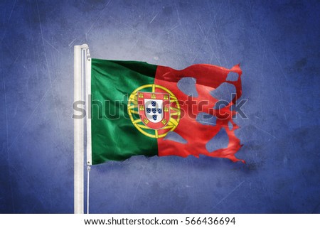 Torn flag of Portugal flying against grunge background.