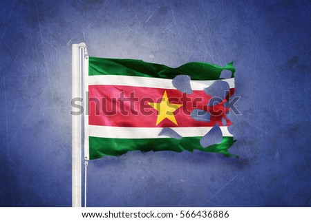 Torn flag of Suriname flying against grunge background.