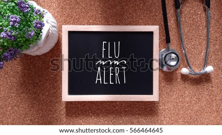 Stethoscope, Chalk board and flower with inscription flu alert on a wooden table. Medical and health care concept.