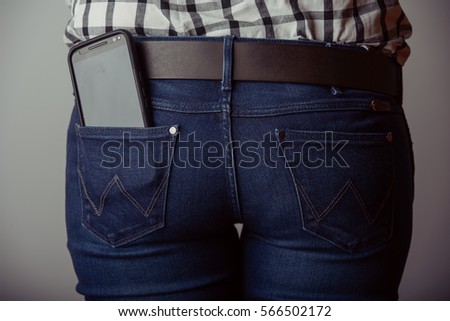 Woman takes out smartphone of her rear pocket of jeans
