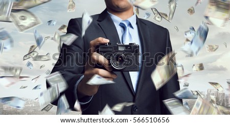 Businessman taking photo with vintage camera . Mixed media