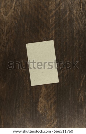 A photo of a grey kraft paper business card on a dark wooden background texture. A mockup or a minimalist banner with copyspace