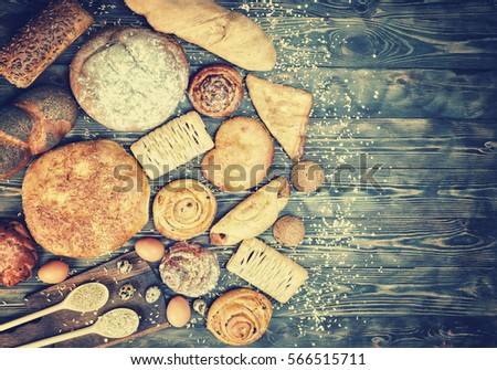 
Bread, rolls, pastries, croissants, eggs, on a dark wooden table. Toning. Royalty-Free Stock Photo #566515711