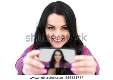 Girl in a plaid shirt makes selfie. Portrait of a smiling cute woman making selfie photo on smartphone isolated on a white background